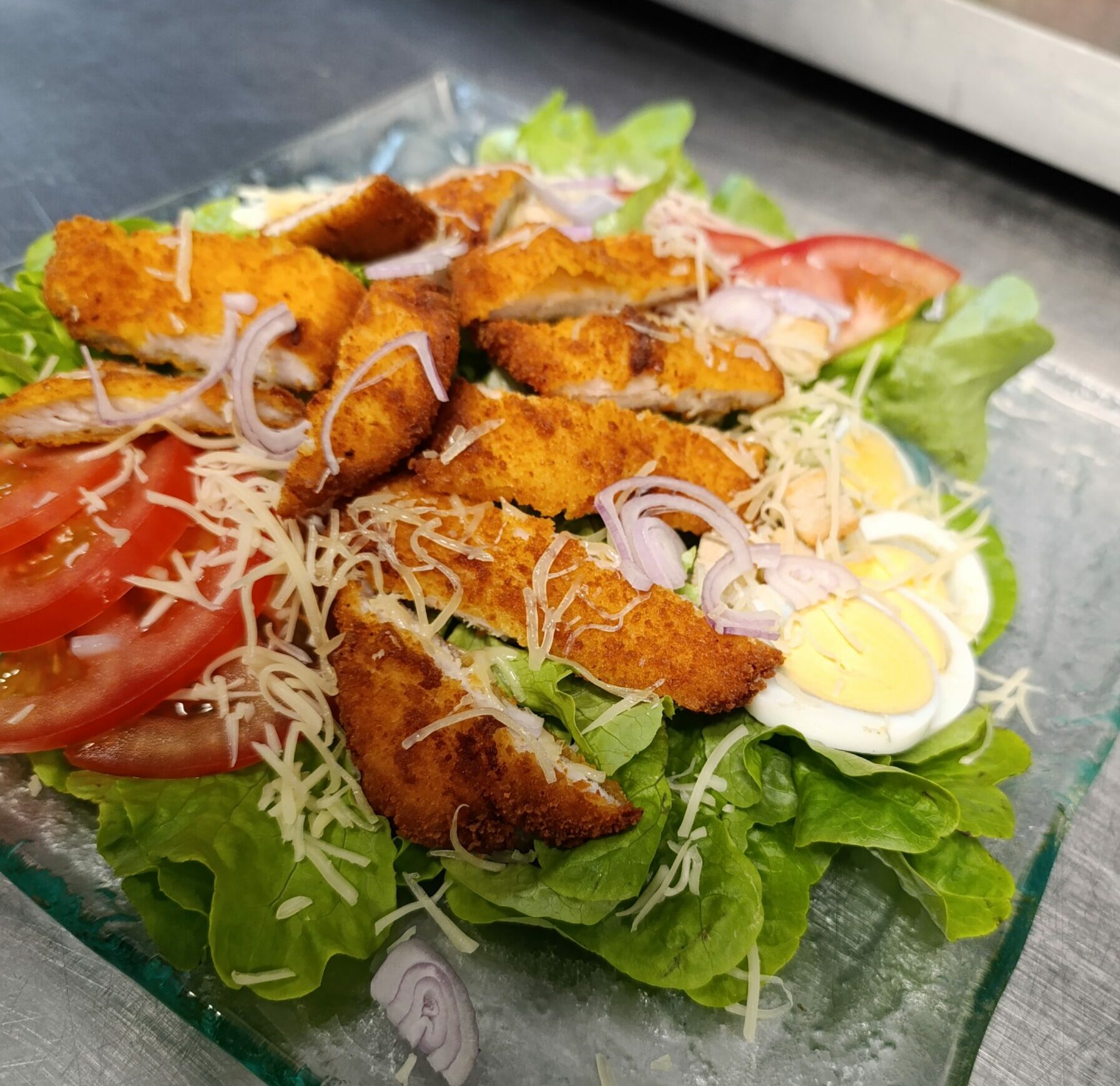 Salade verte, tomate, œuf dur, croûtons, filets de poulet frit, Parmesan, oignons rouges, sauce césar