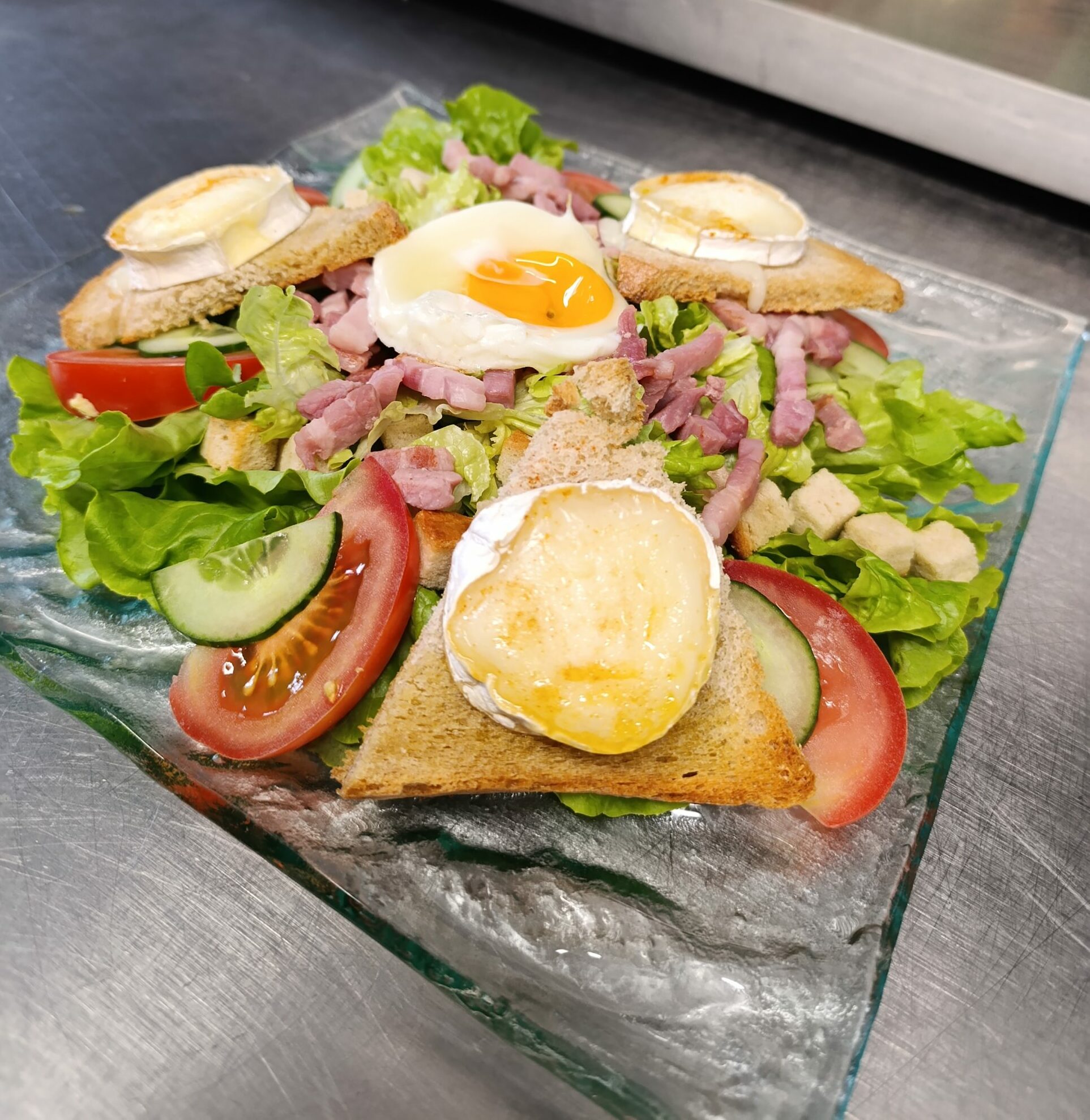 Salade verte, tomate, lardons, fromage de chèvre sur toasts, œuf sur le plat, sauce vinaigrette