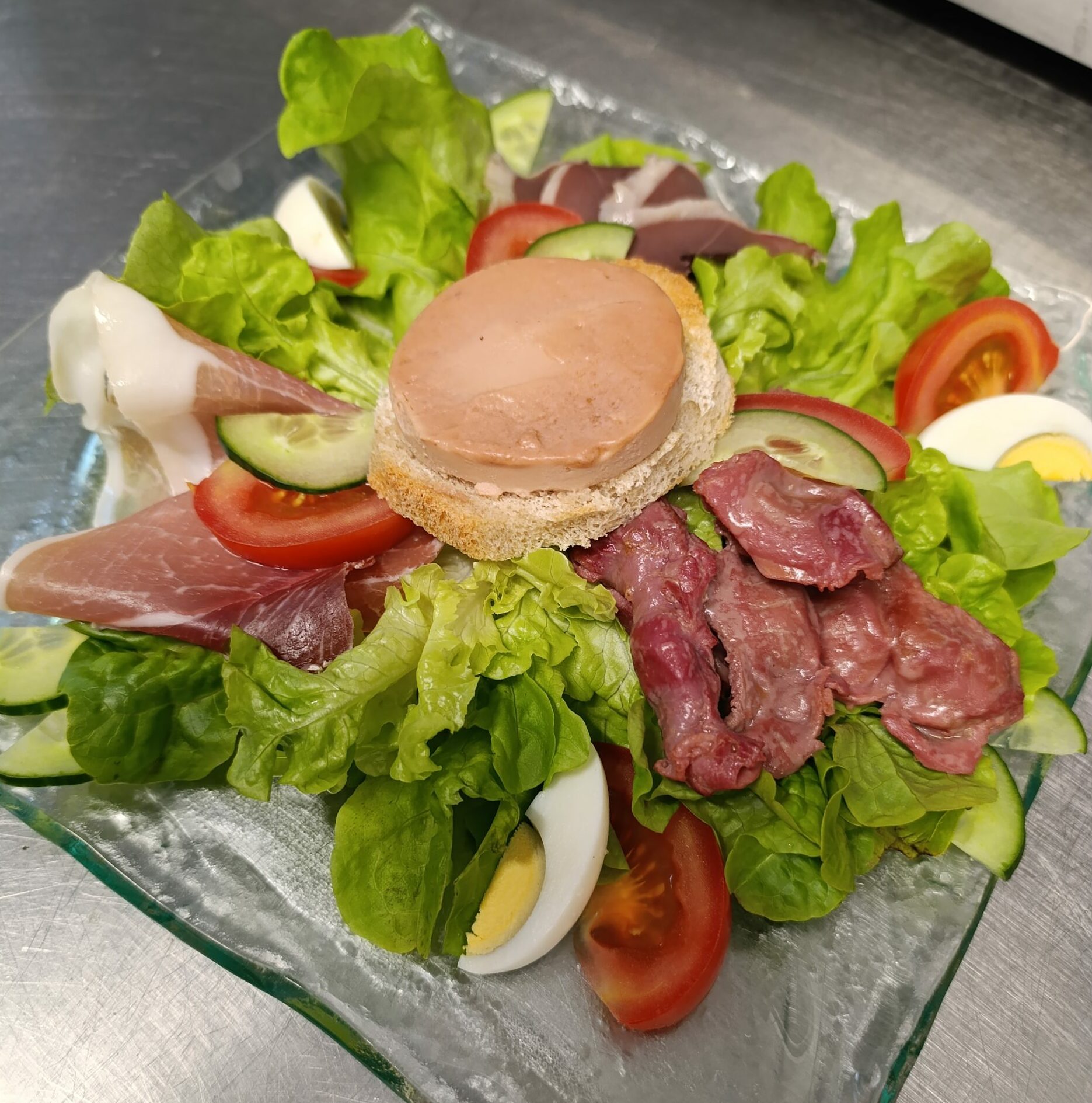 Salade verte, tomate, œuf dur, foie gras sur toast, magret fumé, gésiers confits, jambon de pays, sauce vinaigre de framboise