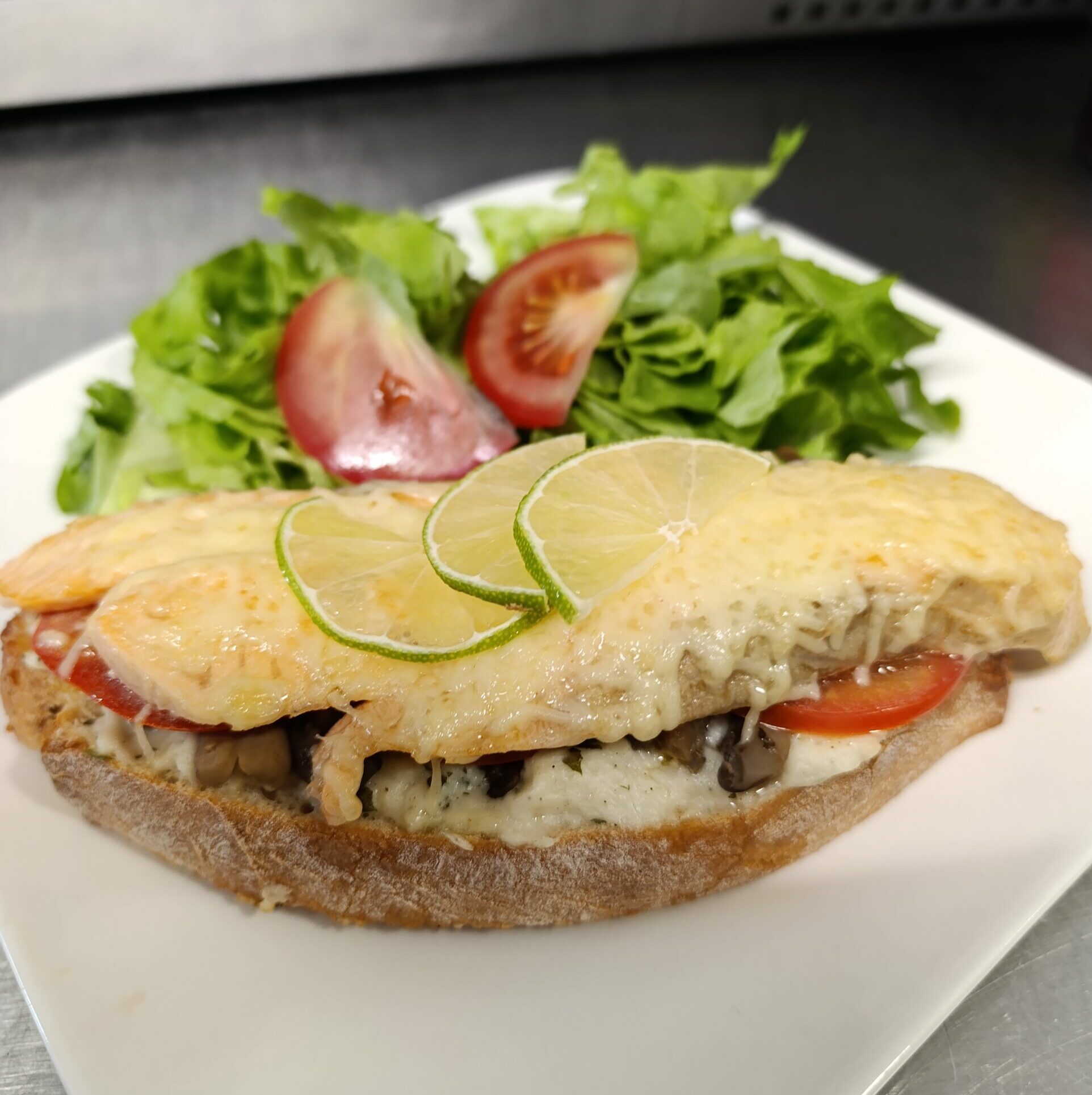 Tartine, béchamel à l’oseille, saumon frais, champignons de Paris, tomate, emmental râpé Accompagnée de salade